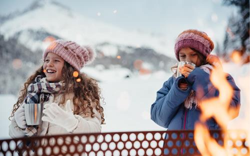 Two girls warm themselves up at the campfire