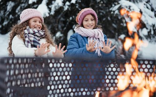 Two girls warm themselves up at the campfire