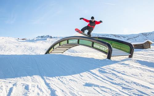 A freestyle snowboarder is doing tricks at the snowpark