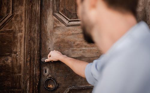 A man in front of an antique door